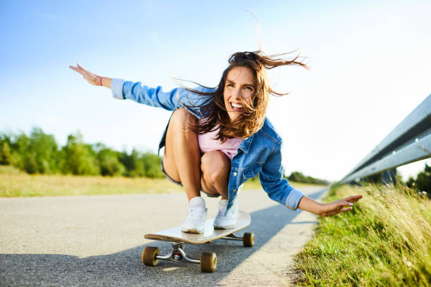 istock Cheerful young woman riding longboard in countryside setting 1031385324