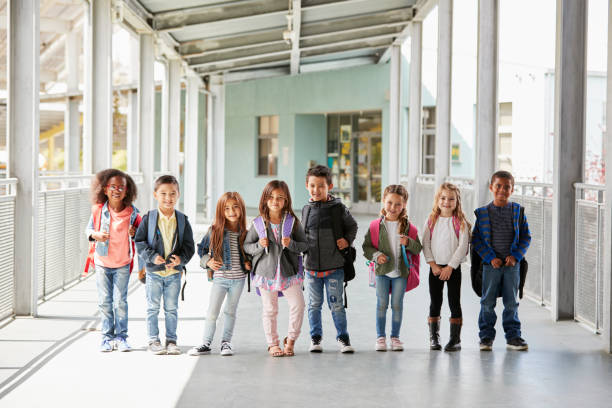 istock Elementary school class standing in corridor with their bags 1031389822
