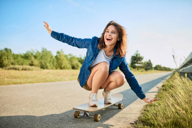 istock Ecstatic woman riding longboard on road in the countryside 1031393792