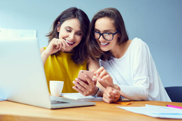 istock Beautiful young office workers using phone and laughing during work break in the office 1031394330