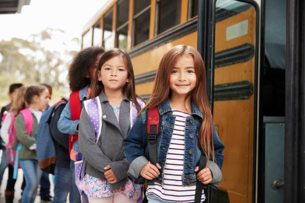 istock Two girls at the front of the elementary school bus queue 1031397102