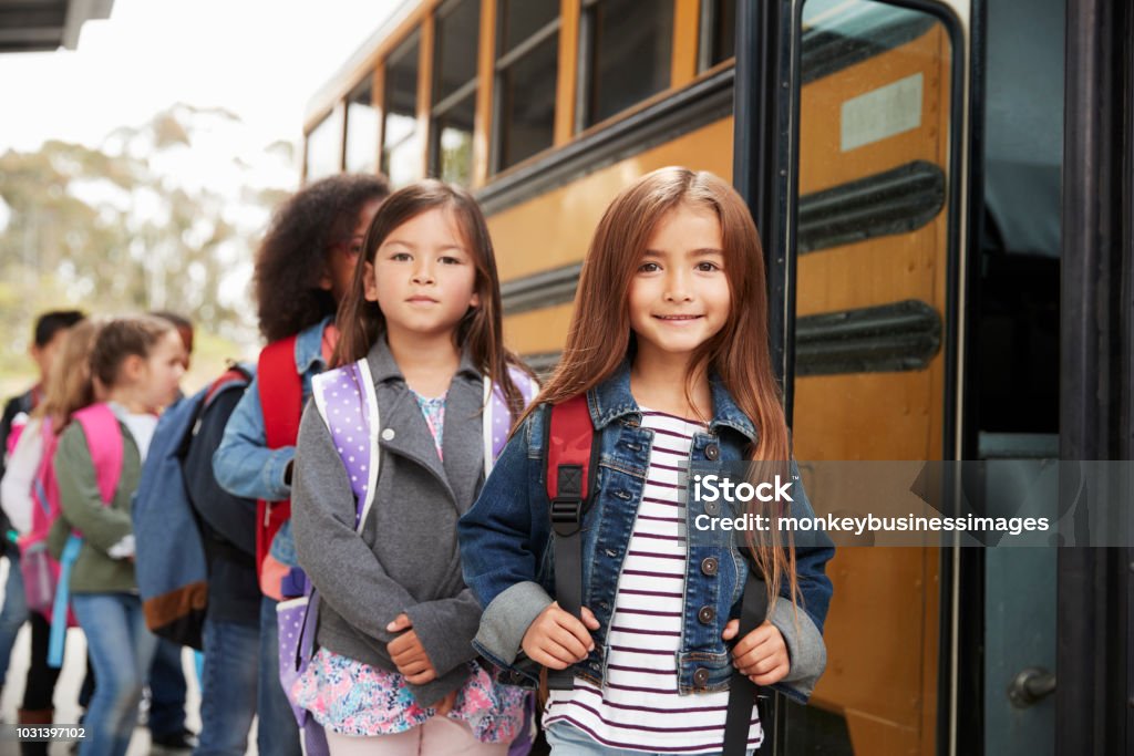 Two girls at the front of the elementary school bus queue School Bus Stock Photo