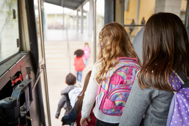 Two girls waiting behind their friends to get off school bus Two girls waiting behind their friends to get off school bus school buses stock pictures, royalty-free photos & images