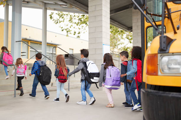 crianças do ensino fundamental chegam na escola de ônibus escolar - autocarro escolar - fotografias e filmes do acervo