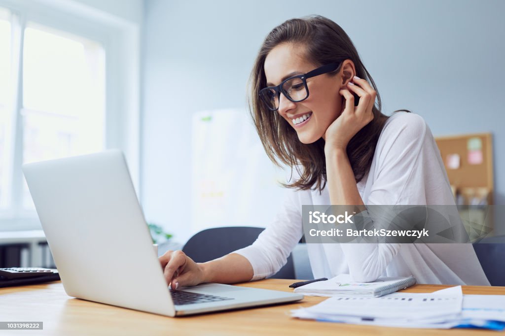 Retrato de hermosa empresaria jóvenes alegre riendo en oficina en casa y trabajando en ordenador portátil - Foto de stock de Mujeres libre de derechos