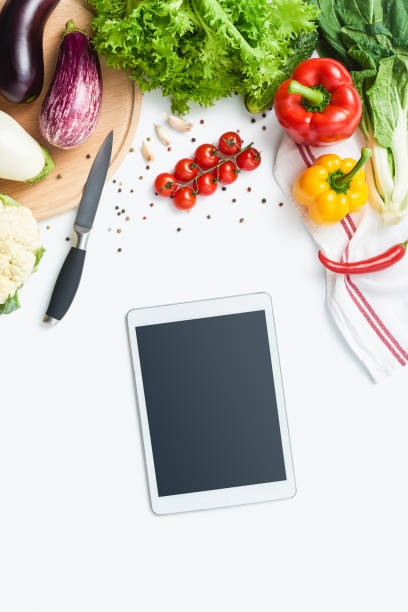 istock digital tablet, knife, cutting board, herbs and vegetables isolated on white background. Copy space 1031400694