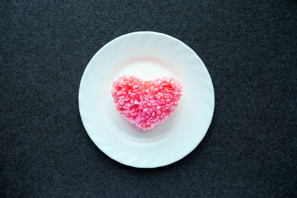 istock Fluffy pink thread heart on heart on a white round plate on a dark felt backgroundd. Handmade pretty heart. Love, romance, Valentines day DIY concept. Flat view 1031404132