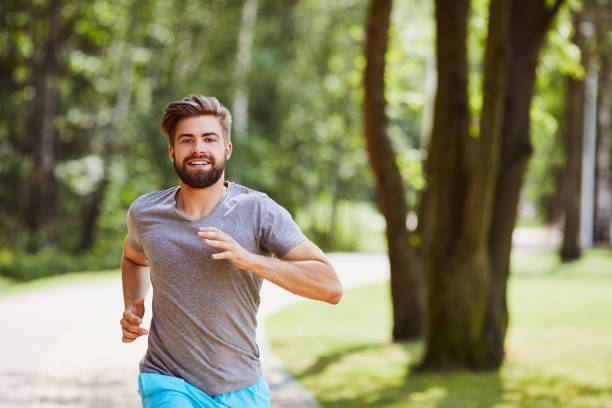 istock Smiling young man running in the park during summer 1031422588