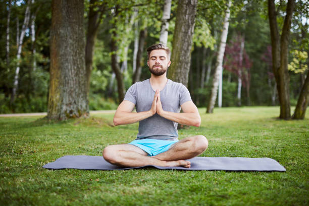 istock Young man in a meditative pose in the park 1031422756