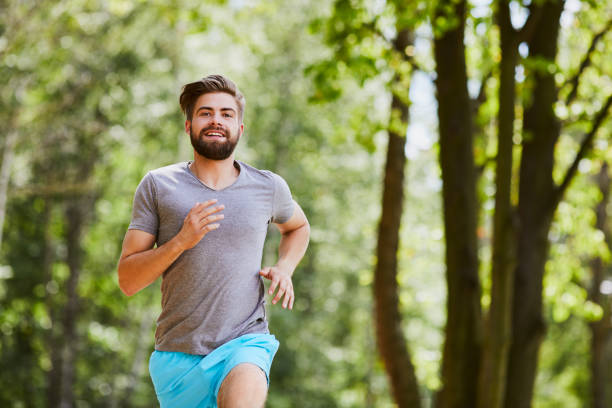 istock Happy young man jogging outdoors in a park in the summer 1031422764