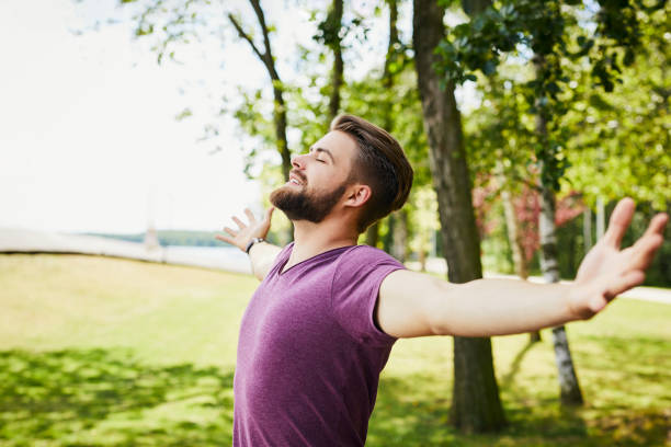 istock Young man extending arms and enjoying the sun outdoors in the park 1031423004