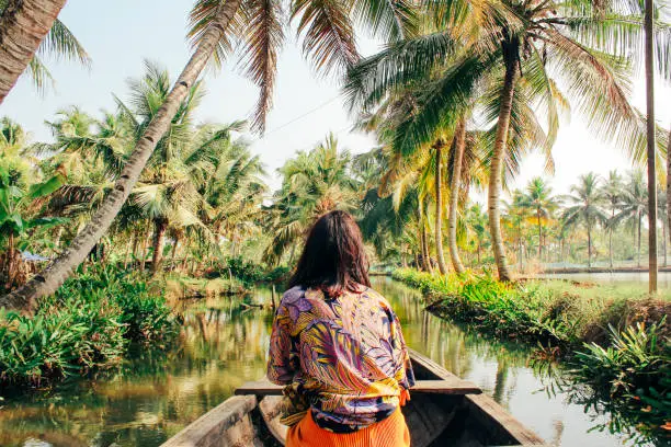 A young woman kayaks through the backwaters of Monroe Island in Kollam District, Kerala, South India.