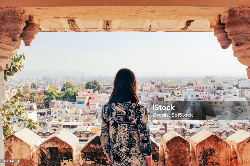 Admiring the City of Udaipur A young woman looks out over the city of Udaipur, Rajasthan, North India. India Stock Photo