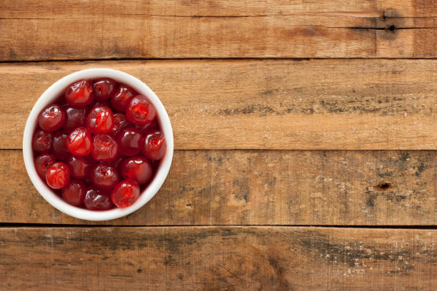 Maraschino cherries Top view of white bowl full of maraschino cherries over wooden table candied fruit stock pictures, royalty-free photos & images