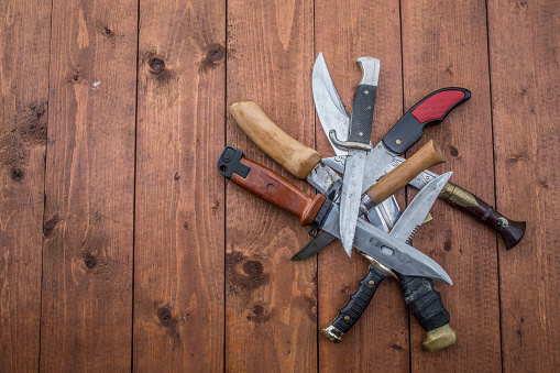 Hunting knives in a pile on a table with copy space