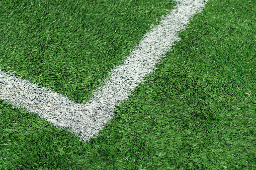 Photo of the details of football field with artificial grass.