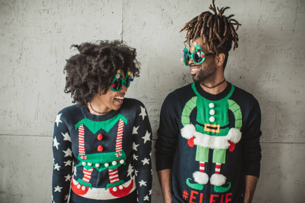 Funny Christmas couple Young couple celebrating Christmas at home. They wear 
 christmas sweaters and funny glasses. christmas sweater photos stock pictures, royalty-free photos & images