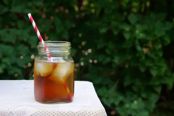 Iced tea in mason jar with red straw on lace table