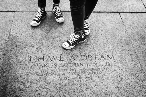 Washington DC, USA - June 2017: Youth in their sneakers standing by the marker engraving memorializing the location of where Martin Luther King made his famous \