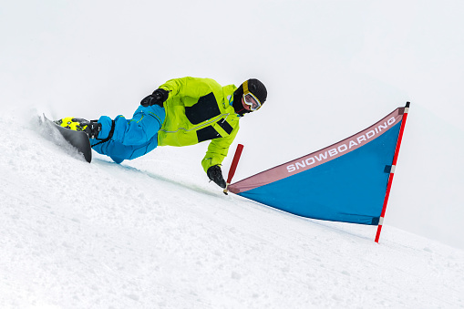 Young male snowboarder practicing parallel giant slalom