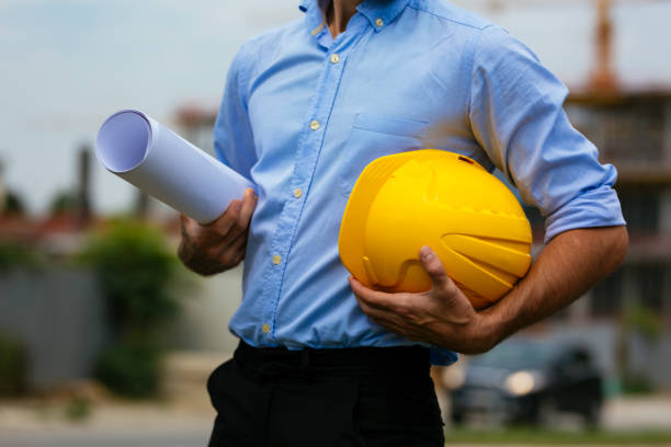 istock Close-up of architect holding blueprints and hardhat 1031477784
