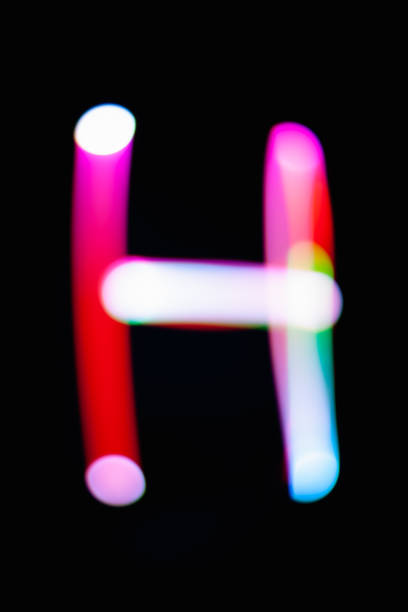 Letter H. Glowing letters on dark background. Abstract light painting at night. Creative artistic colorful bokeh. New Year. Use it for build you own design for book cover, CD, poster or post card.