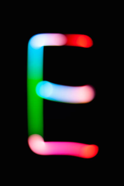 istock Letter E. Glowing letters on dark background. Abstract light painting at night. Creative artistic colorful bokeh. New Year. Use it for build you own design for book cover, CD, poster or post card. 1031481794
