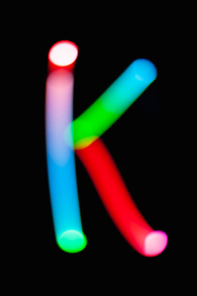 istock Letter K. Glowing letters on dark background. Abstract light painting at night. Creative artistic colorful bokeh. New Year. Use it for build you own design for book cover, CD, poster or post card. 1031481798
