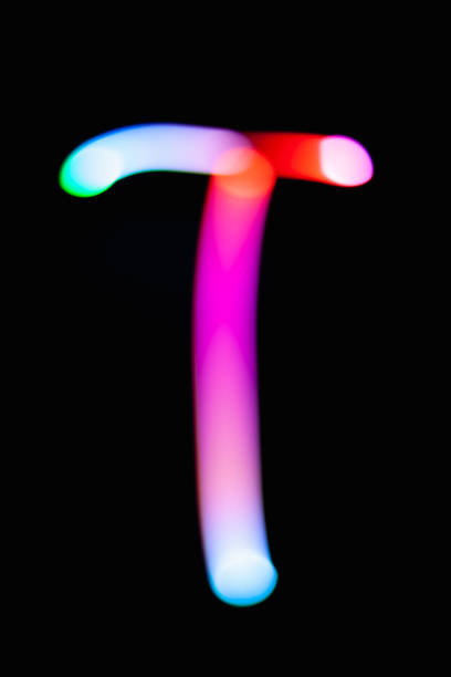 istock Letter T. Glowing letters on dark background. Abstract light painting at night. Creative artistic colorful bokeh. New Year. Use it for build you own design for book cover, CD, poster or post card. 1031481852