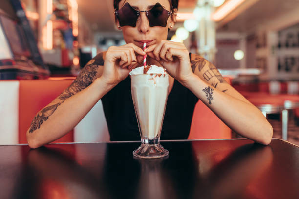 istock Woman drinking milkshake with a straw sitting at a diner 1031497090