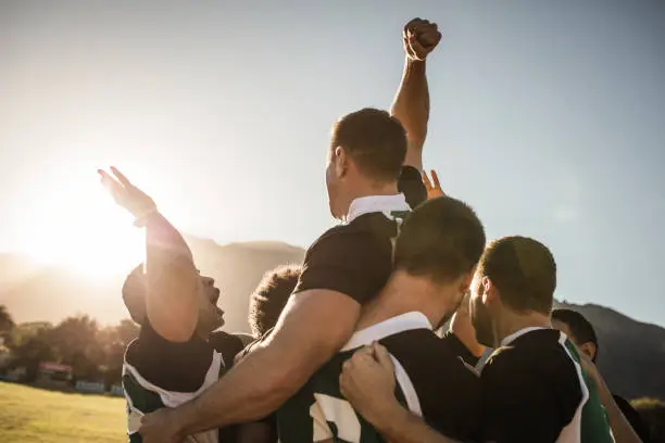 Rugby players lifting the teammate after winning the game. Rugby team celebrating the victory.