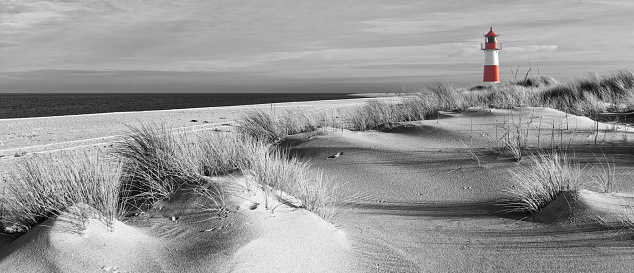 Sand dunes with lighthouse at Ellenbogen on island Sylt, Schleswig-Holstein, Germany. Black and white development with colored lighthouse (RGB-file)