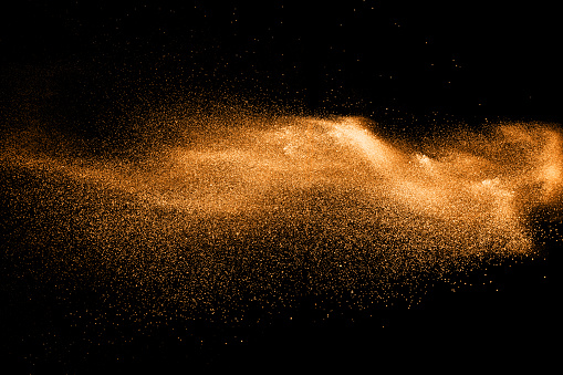 explosión de partículas de polvo naranja sobre fondo negro. Salpicaduras de polvo de polvo de color. photo