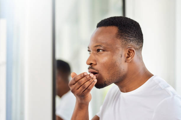 The mandatory morning breath check Shot of a handsome young man smelling his breath during his morning grooming routine breath vapor stock pictures, royalty-free photos & images