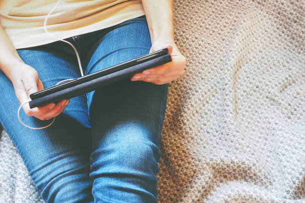 istock Legs in jeans, tablet in hands on a gray blanket. Concept training and recreation. 1031528926