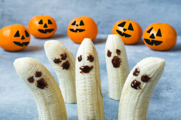 istock Painted funny faces on tangerines and bananas for Halloween 1031529476