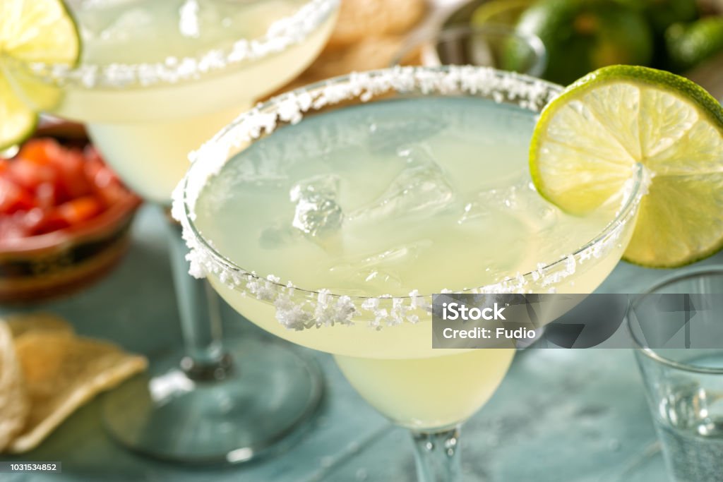 Tequila and Lime Margaritas Delicious tequila and lime margaritas on an outdoor table with tortilla chips and pico de gallo. Margarita Stock Photo
