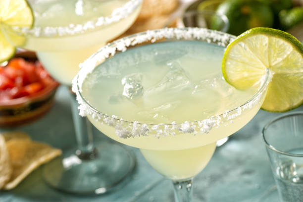 Tequila and Lime Margaritas Delicious tequila and lime margaritas on an outdoor table with tortilla chips and pico de gallo. margarita stock pictures, royalty-free photos & images