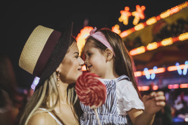 Lovely mother and daughter having fun at a festival Cute and lovely mother and daughter spending their time together at a amusement park, having fun. festival goer stock pictures, royalty-free photos & images