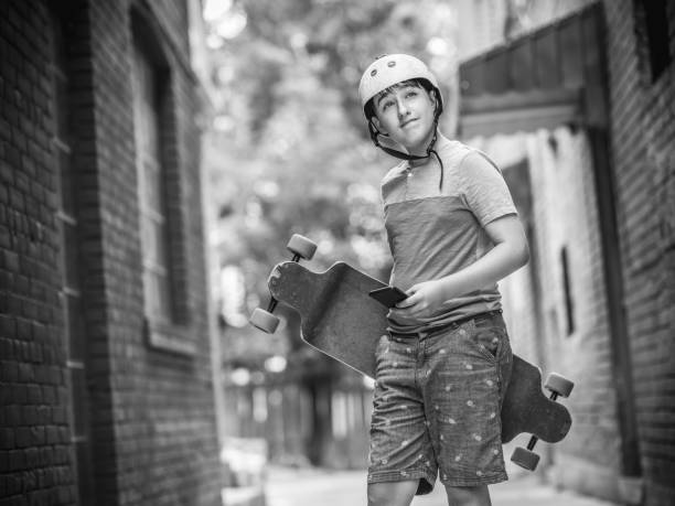 Teenage boy with his long board along the city street and using mobile phone.
