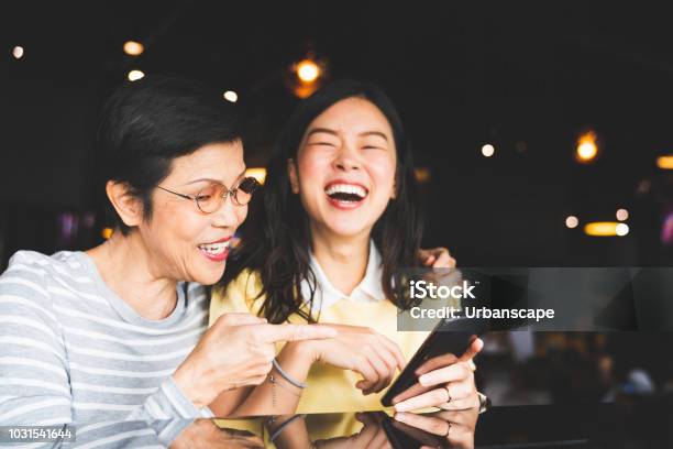 Asian Mother And Daughter Laughing And Smiling On A Selfie Or Photo Album Using Smartphone Together At Restaurant Or Cafe With Copy Space Family Love Holiday Activity Or Modern Lifestyle Concept Stock Photo - Download Image Now