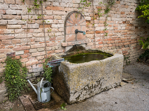 Stone trough standing in front of a brick wall in a garden