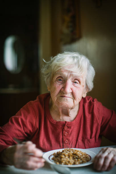 istock An elderly woman eats sitting at the table. 1031551812