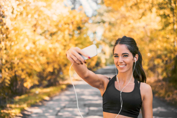 istock Beautiful girl smiling and taking selfie while running in park. 1031563776