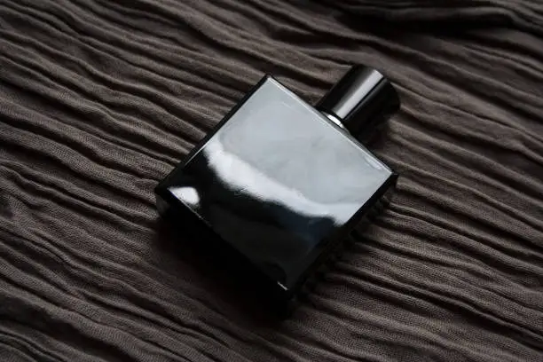 Photo of Dark blue glass perfume bottle on textured fabric