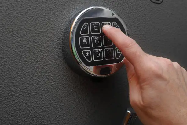 Hand enters combination on a digital lock of a safe's door
