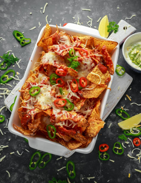 istock Maxican-style tortilla nachos chips topped with tomato salsa, sliced chilies and melted cheese served with lemon wedges and avocado yogurt dip 1031570842