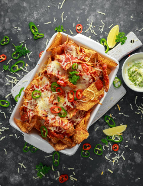 istock Maxican-style tortilla nachos chips topped with tomato salsa, sliced chilies and melted cheese served with lemon wedges and avocado yogurt dip 1031570856