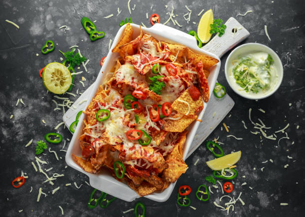 istock Maxican-style tortilla nachos chips topped with tomato salsa, sliced chilies and melted cheese served with lemon wedges and avocado yogurt dip 1031570876