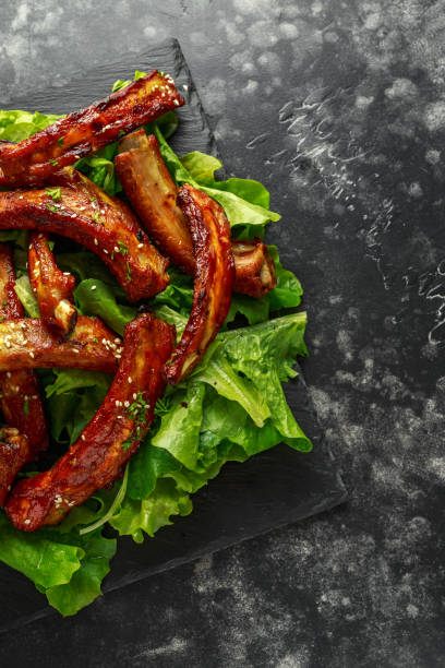 istock Roasted barbecue hot pork ribs served on stone board with vegetable 1031571278